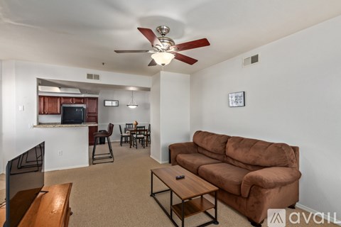 A living room with a brown couch and a ceiling fan.
