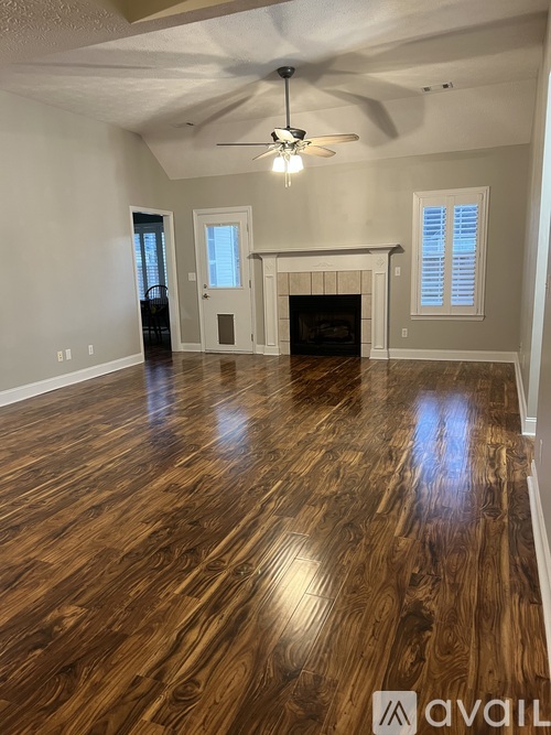 A spacious room with wood flooring and a fireplace.