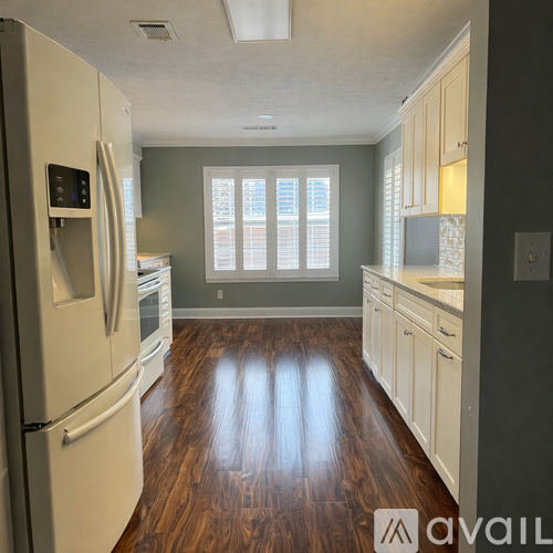 A kitchen with a white refrigerator and wooden floors.