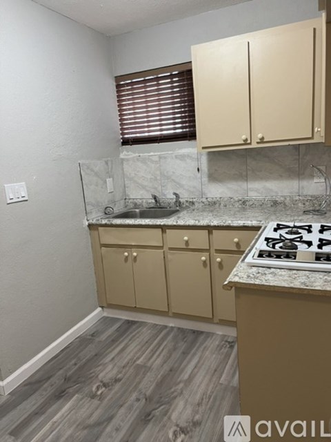 A kitchen with a marble countertop and wooden cabinets.