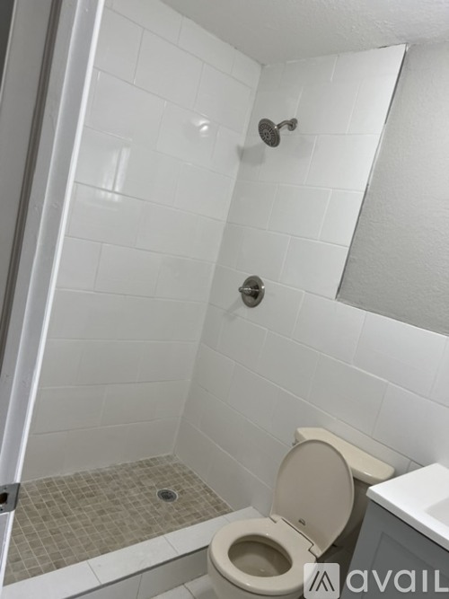 A white toilet in a bathroom with a white tiled shower.