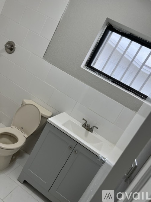 A bathroom with a toilet, sink, and a window.