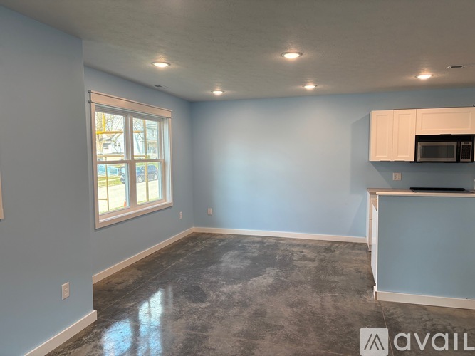 A room with a window and a microwave oven on a counter.