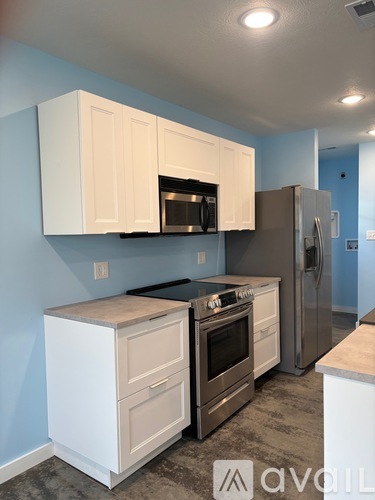 A kitchen with white cabinets and a stainless steel refrigerator.