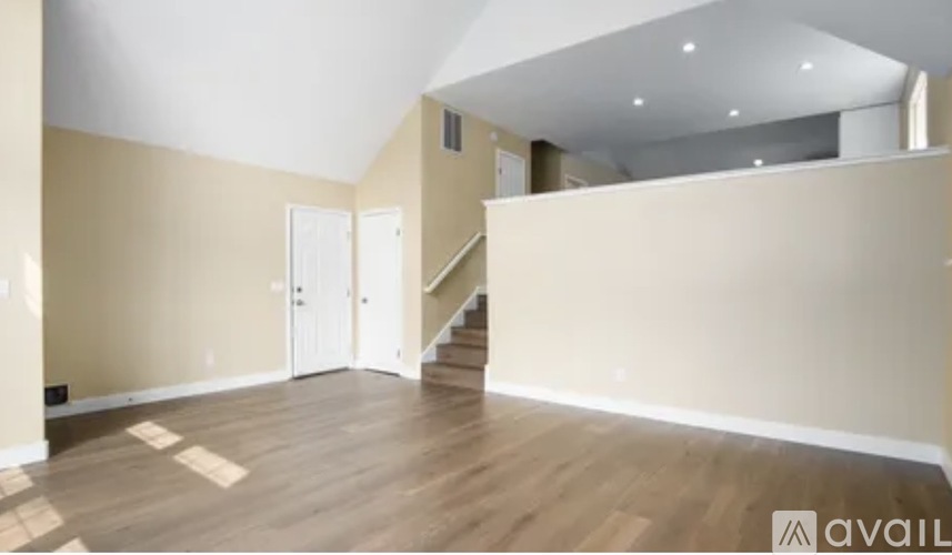 A spacious room with wooden flooring and a staircase leading to another level.