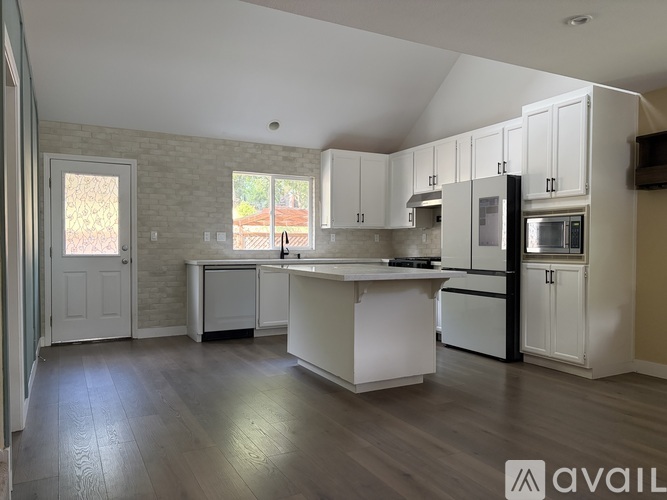 A kitchen with white cabinets and a wooden floor.