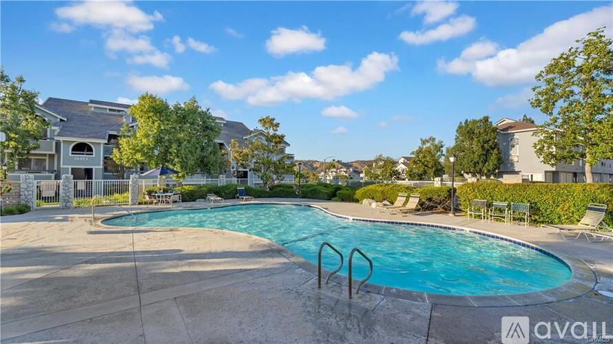 A swimming pool surrounded by a concrete patio and a fence.