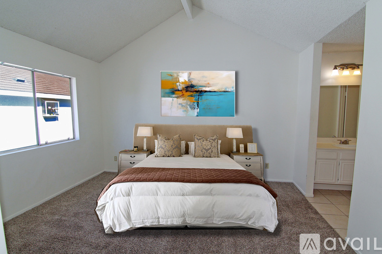 A bedroom with a large bed and a painting on the wall.