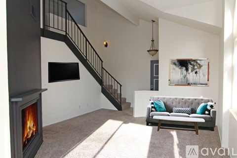 A living room with a grey couch and a fireplace.
