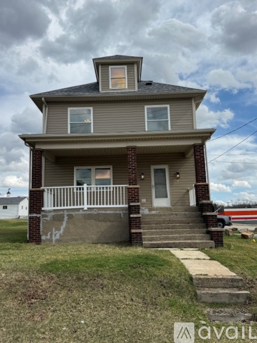 A two-story house with a grey siding and a white porch.