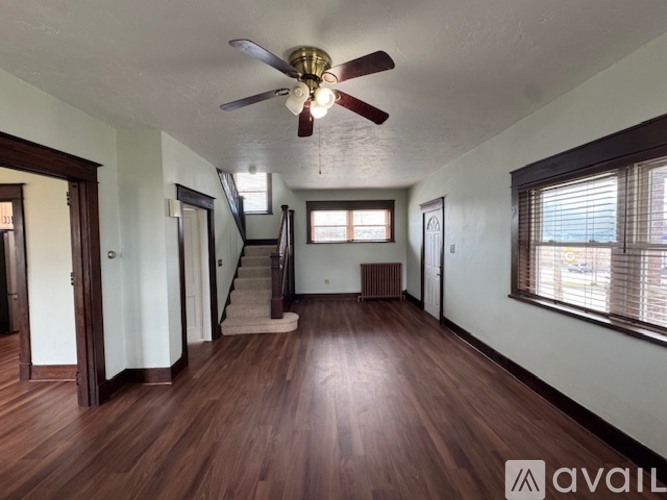 A spacious room with wood flooring and a ceiling fan.