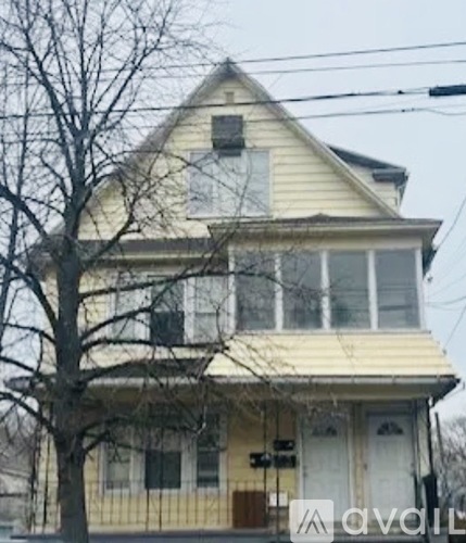 A yellow house with a tree in front of it.