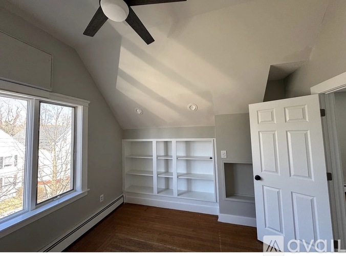 A room with a ceiling fan and a large window.