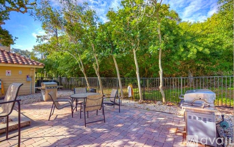 A patio with a table and chairs surrounded by trees.