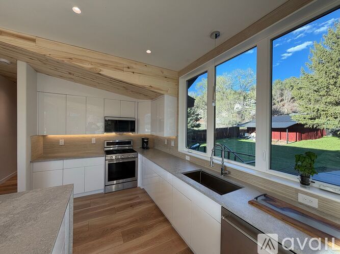 A modern kitchen with wooden cabinets and a large window.