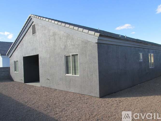 A grey building with a pitched roof and a small window on the side.