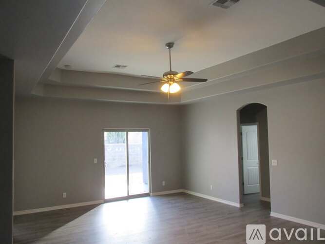 A spacious room with a ceiling fan and sliding glass doors.