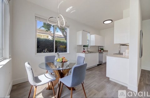 A modern kitchen with a dining table set up with four chairs.