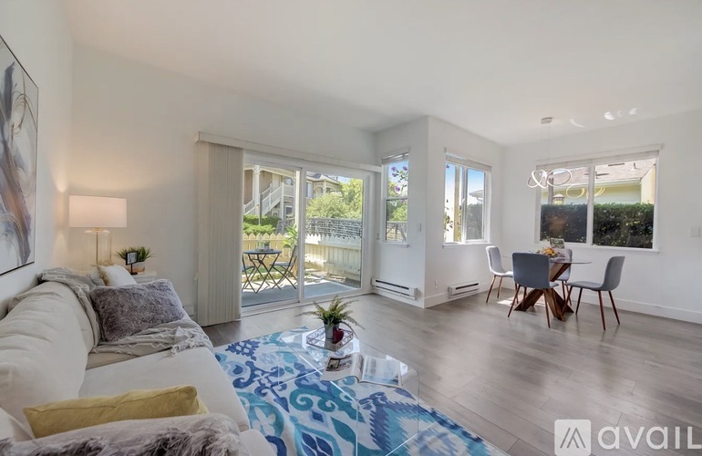 A living room with a white couch and a blue patterned rug.