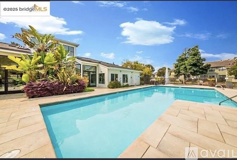 A swimming pool in a backyard with a house in the background.