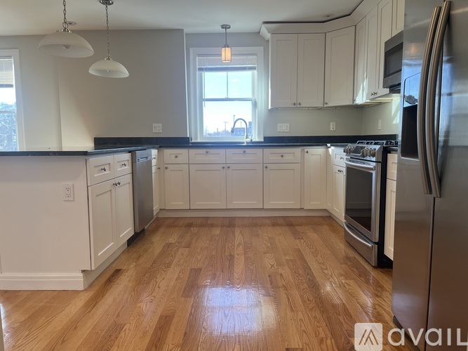 A kitchen with wooden floors and white cabinets.