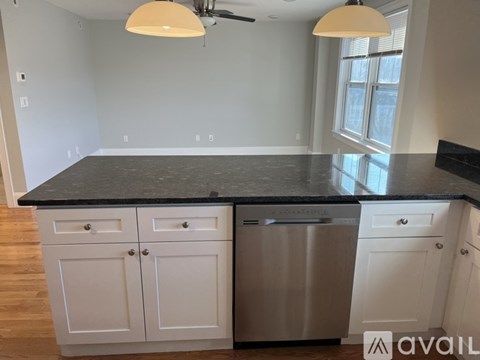 A kitchen with white cabinets and a black countertop.