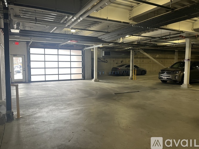 A spacious garage with a car parked on the right side and a door on the left.