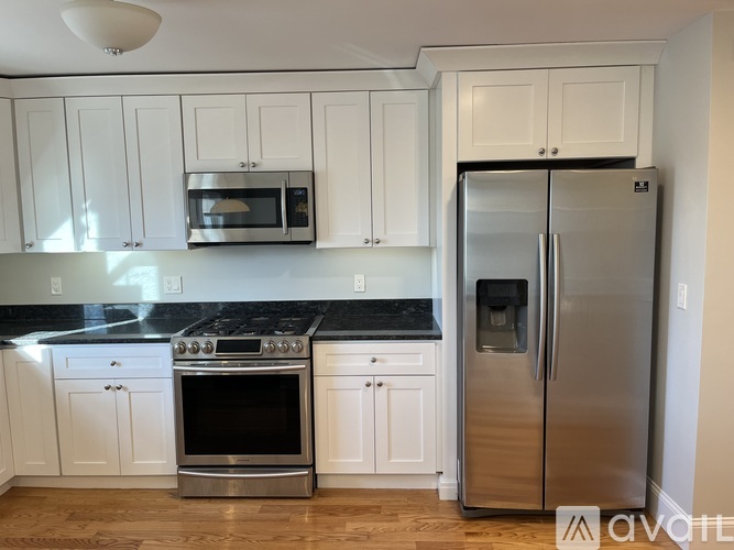 A kitchen with white cabinets and a stainless steel refrigerator.