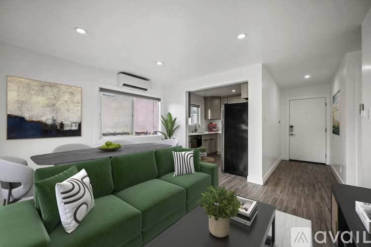 A living room with a green couch and a painting on the wall.