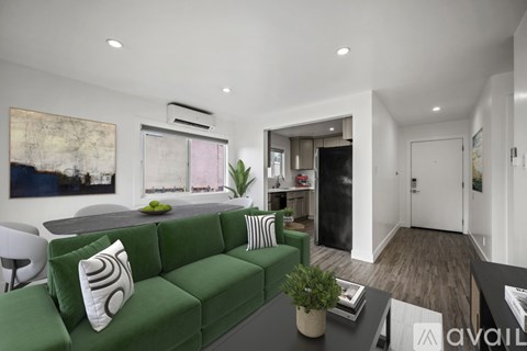 A living room with a green couch and a painting on the wall.