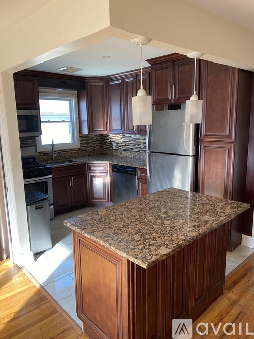 A kitchen with a granite countertop and wooden cabinets.