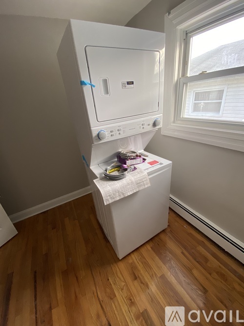 A white dishwasher is in a kitchen with wooden floors.