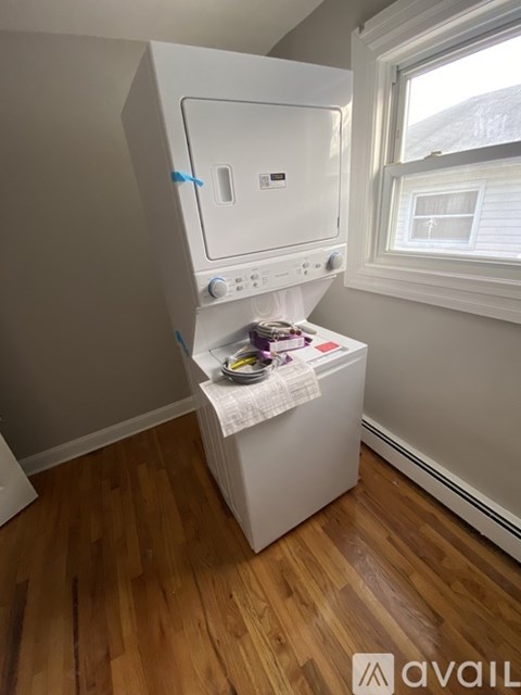 A white dishwasher is in a kitchen with wooden floors.