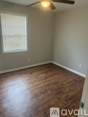 A room with wooden flooring and a window with blinds.