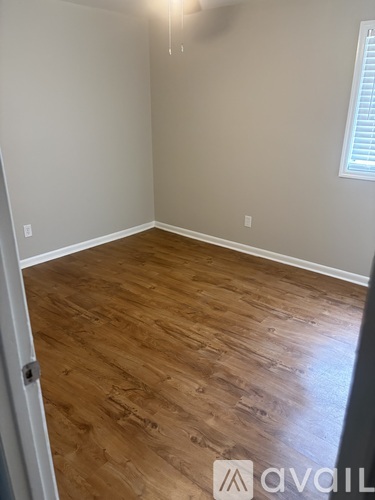A room with wooden flooring and a window with blinds.