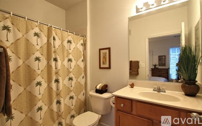 A bathroom with a beige shower curtain with palm trees on it.