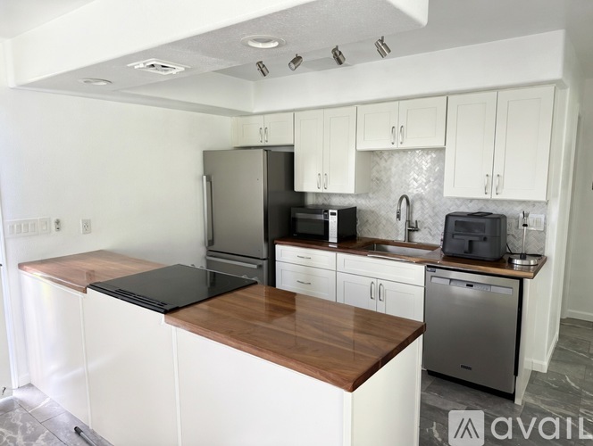 A kitchen with white cabinets and a wooden island.