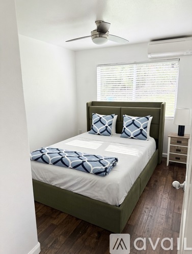A bedroom with a bed, pillows, and a ceiling fan.