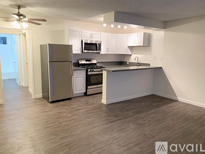A kitchen with a refrigerator, microwave, oven, and stove top.