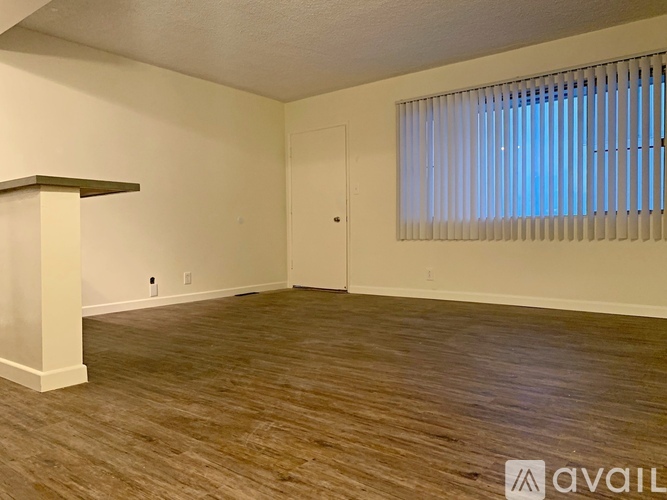 A room with wooden flooring and a window with blinds.