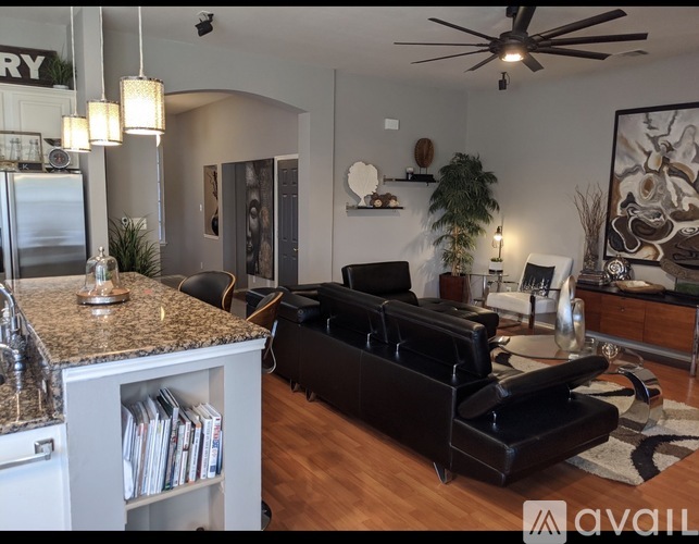 A modern kitchen with a black leather sofa and a ceiling fan.