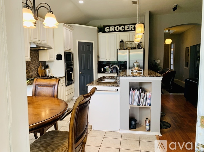 A kitchen with a table and chairs and a sign that says "Grocer" on the wall.