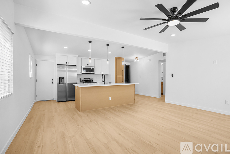A spacious kitchen with wooden floors and a ceiling fan.