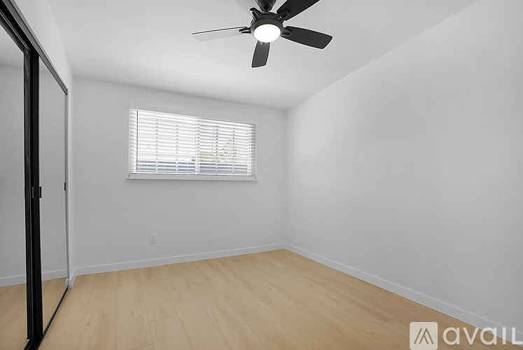A room with a ceiling fan and a window with blinds.