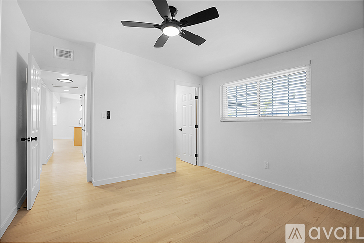 A spacious room with a ceiling fan and wooden flooring.