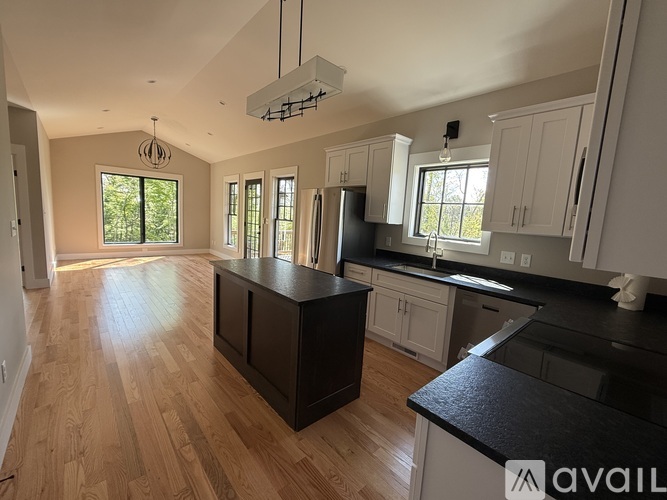 A kitchen with wooden floors and black countertops.