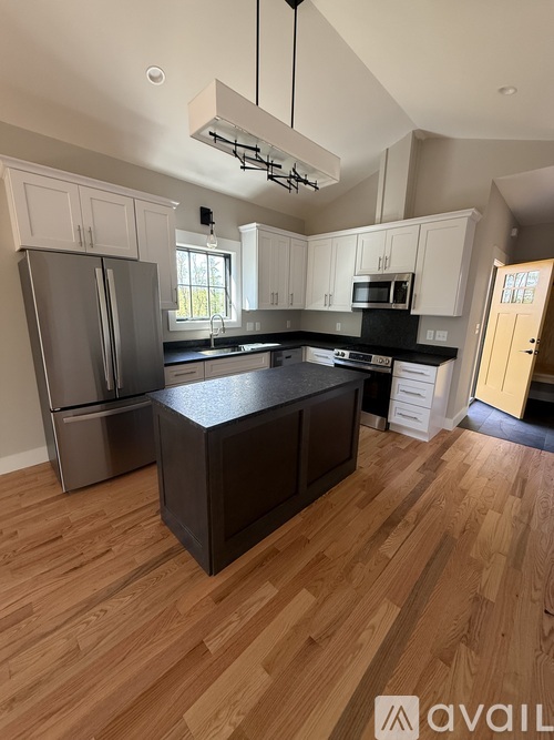 A kitchen with wooden floors and a black island.