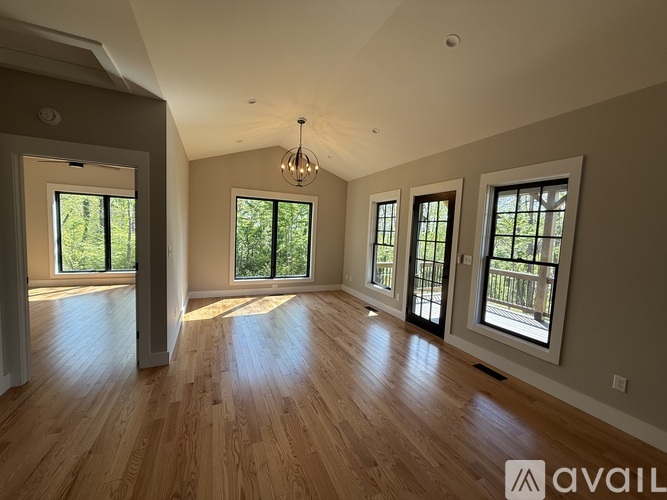 A spacious room with wooden floors and large windows.