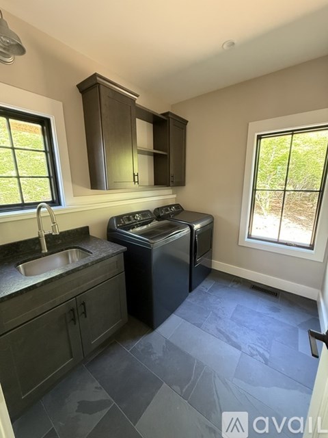 A kitchen with a black fridge, black cabinets, and a black counter top.