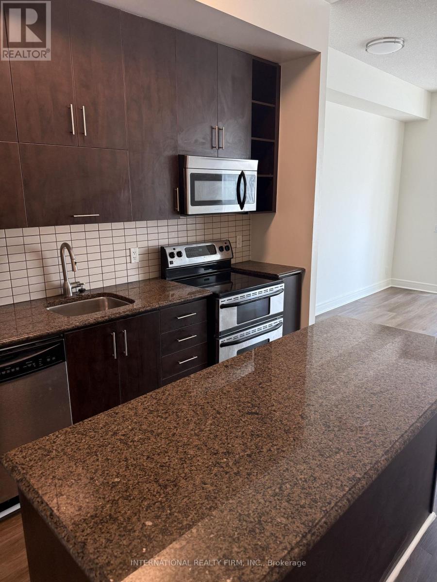 A kitchen with dark brown cabinets and a granite countertop.